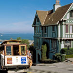 Un cable car passa davanti ad una casa caratteristica di San Francisco 