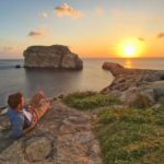 Un uomo osserva il tramonto sulle scogliere di Gozo, Malta