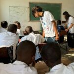 Two volunteers help the students of the Ghomme Secondary School write their scripts for a digital journal course
