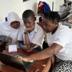 A volunteer supervises students of the Ghomme Secondary School while they take the Cybersecurity course with the Cisco Networking Academy