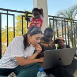 A volunteer introduces a student to a videoediting app and provides basic knowledge of post production