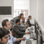 Students in the computer room at CES Leeds with teacher assistance