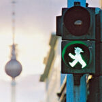 The green ampelmann, one of Berlin's iconic traffic lights with Alexanderplatz's Fernsehturm (television tower)